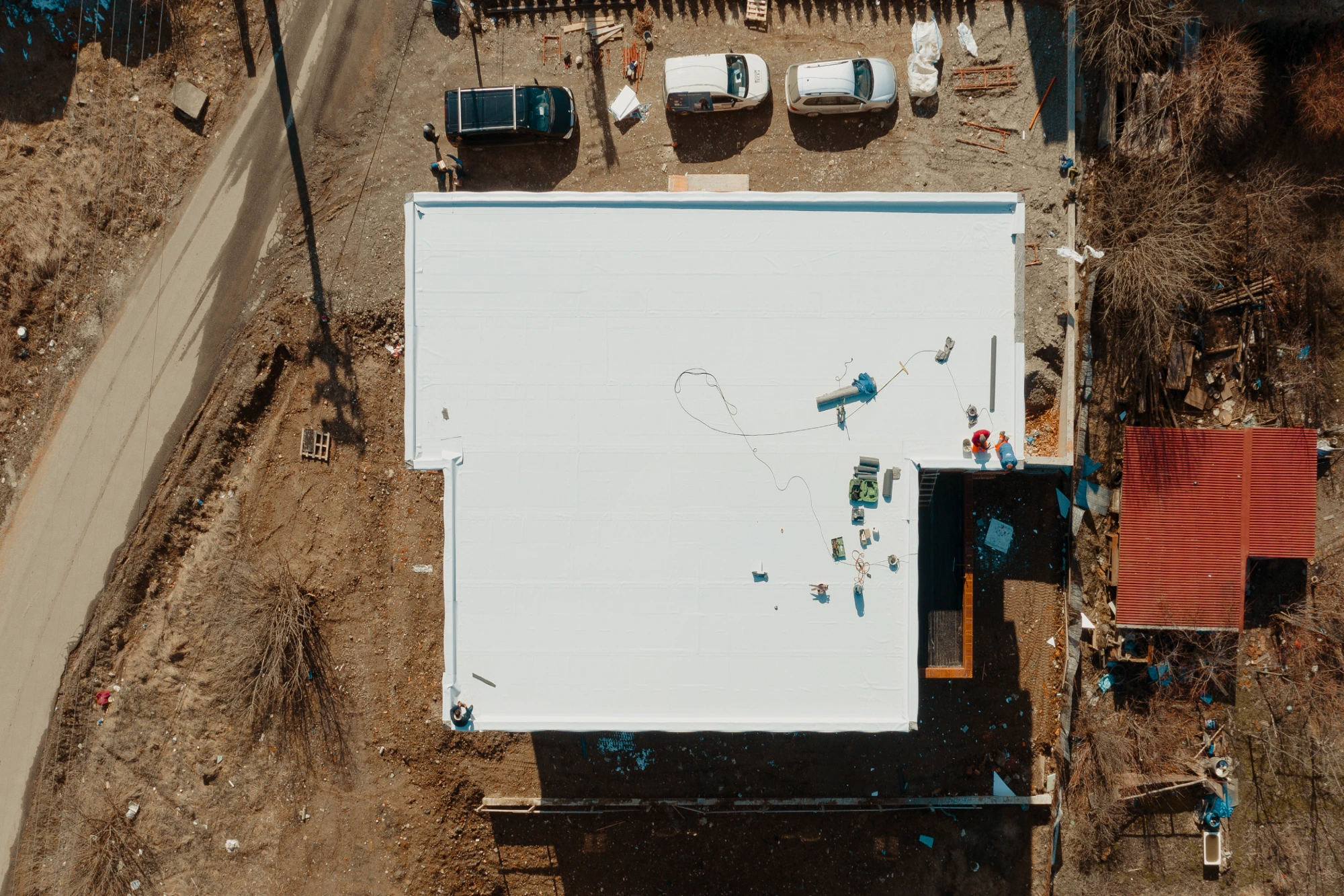Aerial view of a commercial building roof installation with white membrane roofing system and workers on site in West Texas